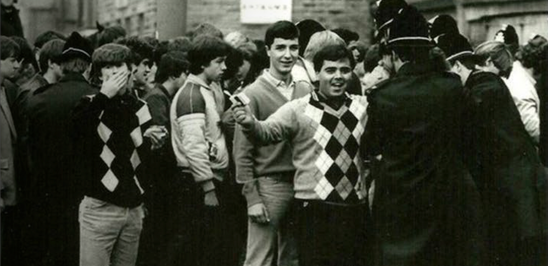 football casuals of the 80s dressed in bold argyle jumpers facing off the police