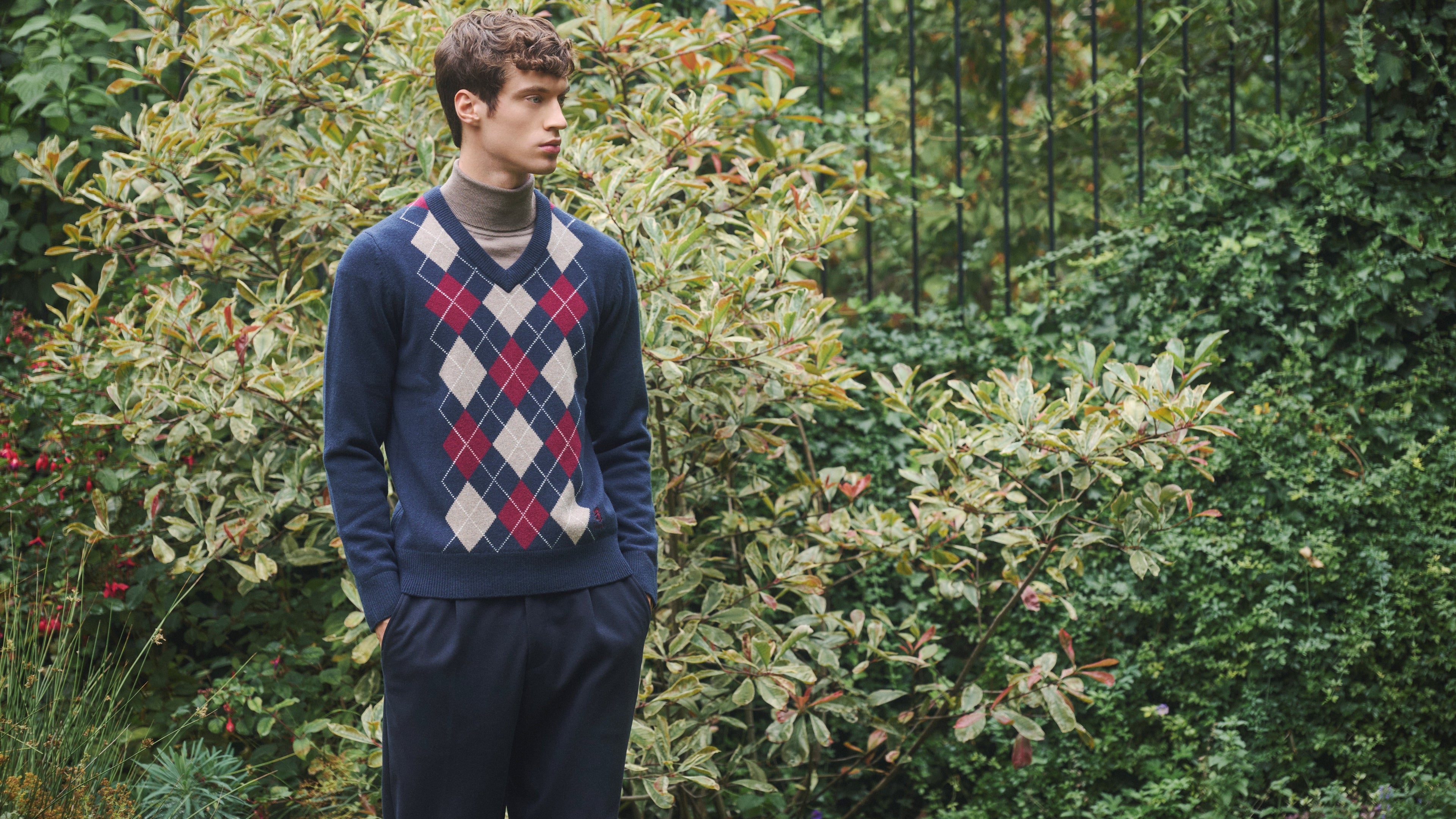 Man wearing a Pringle Argyle jumper against a garden background