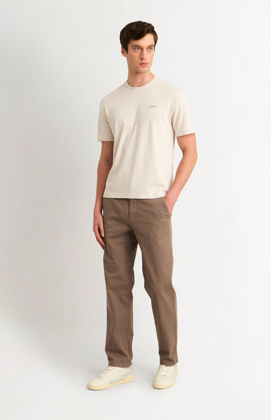 Man wearing an Ecru t-shirt and brown trousers on a white background