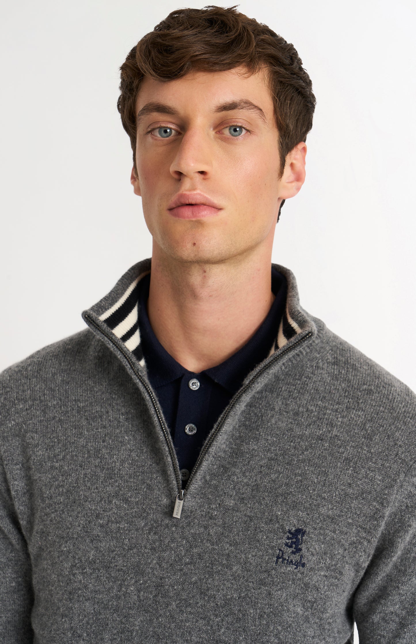 Man wearing a gray sweater with a zipper and a Pringle logo on a light gray background