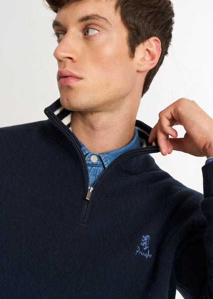 Man wearing a navy sweater with a Pringle lion logo detail shot