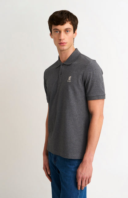 Man wearing a dark gray polo shirt with a small logo on a white background