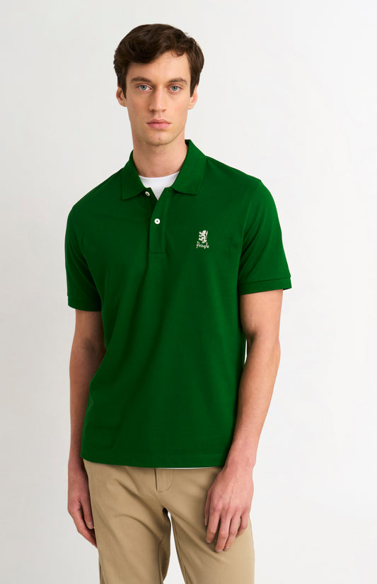 Man wearing a green polo shirt with a logo on a white background