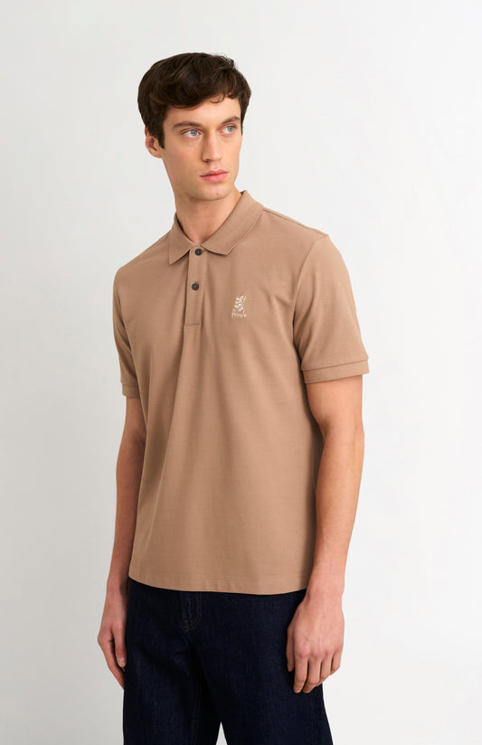 Man wearing a brown polo shirt with a small logo on a white background