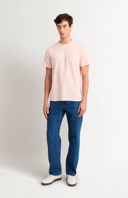 Man wearing a light pink t-shirt and blue jeans on a white background