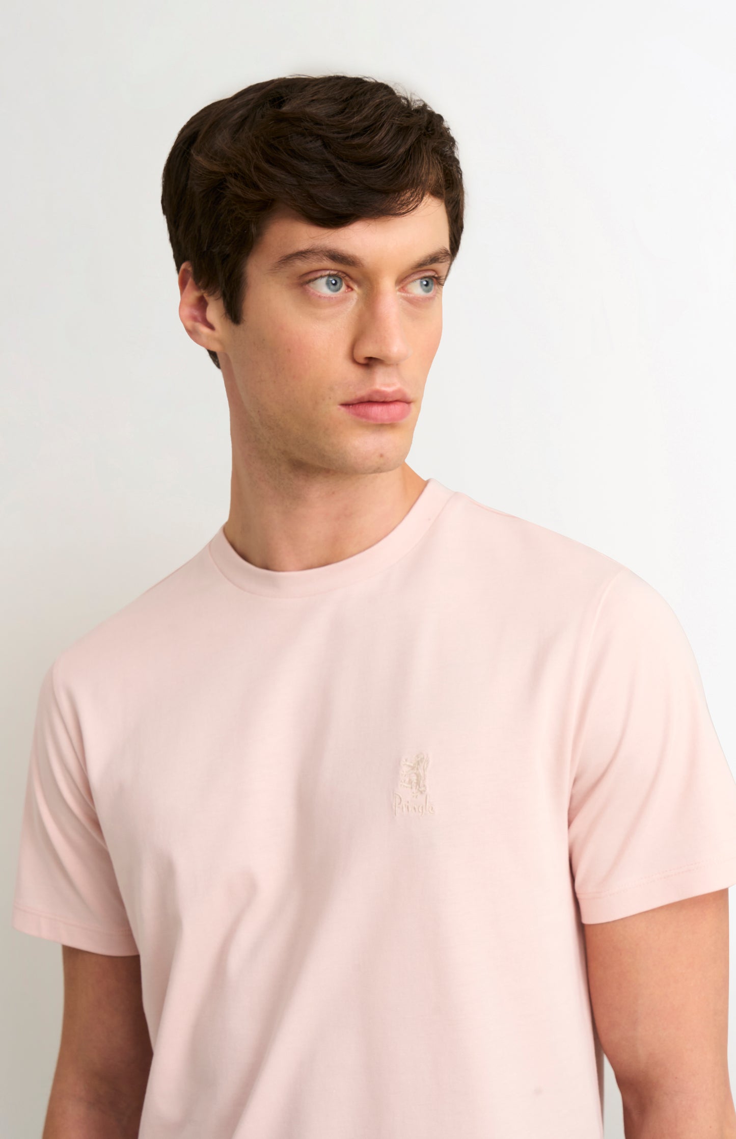 Man wearing a light pink t-shirt against a plain background