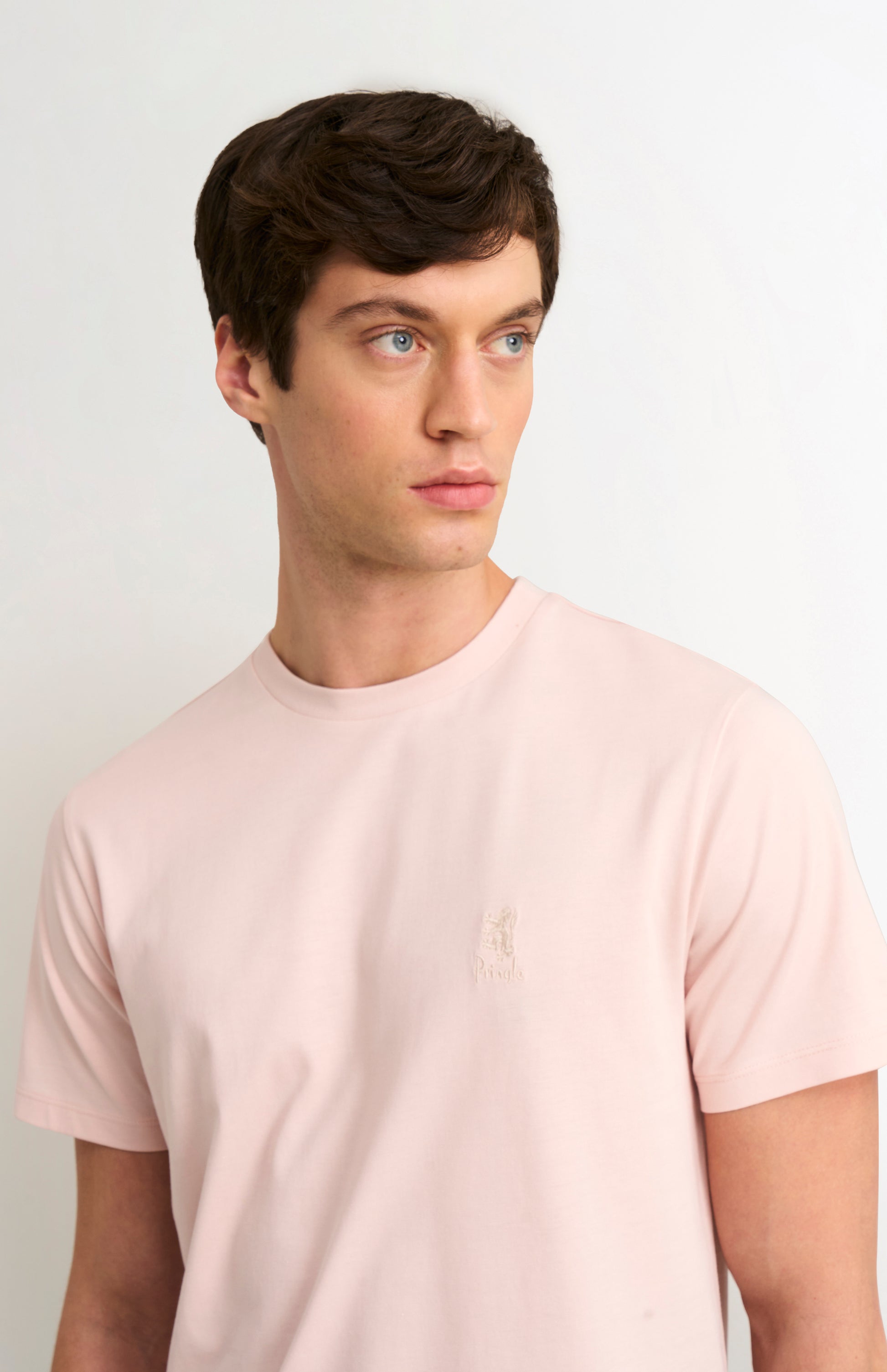 Man wearing a light pink t-shirt against a plain background