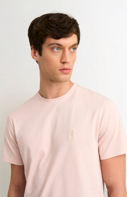 Man wearing a light pink t-shirt against a plain background