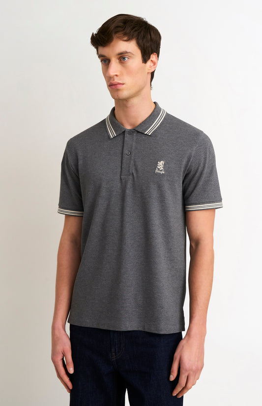Model wearing a charcoal grey polo with white tipping details and a Pringle logo on the upper side of the chest