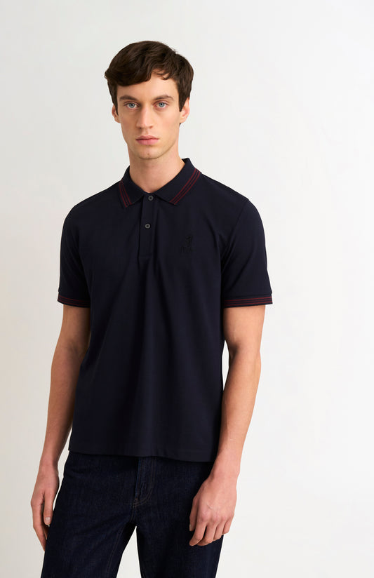 Model wearing a navy polo shirt with burgundy tipping details and Pringle logo on upper side of chest