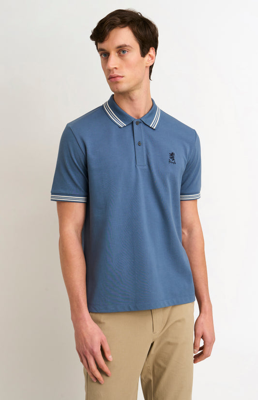 Man wearing a mid blue polo with tipping details and Pringle logo on upper side of chest