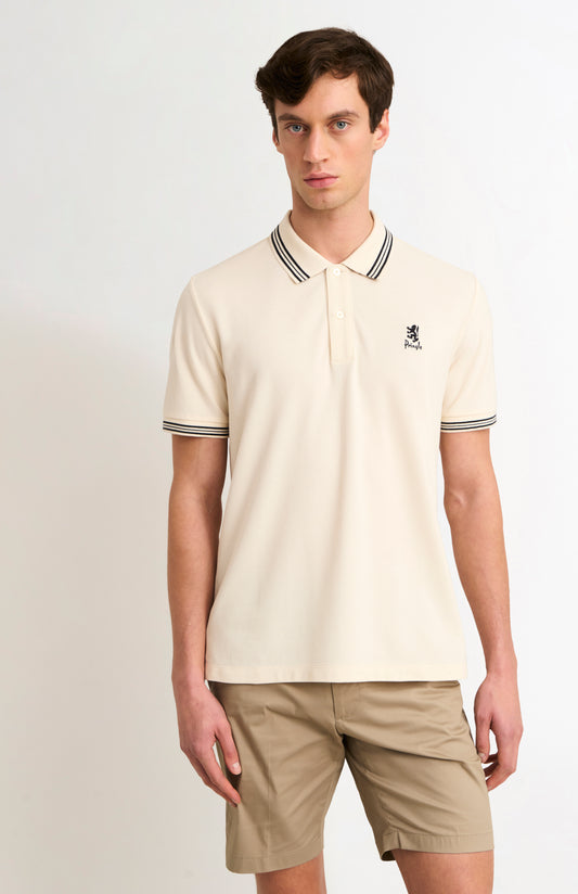 Man wearing a beige polo shirt with a small logo on a plain background