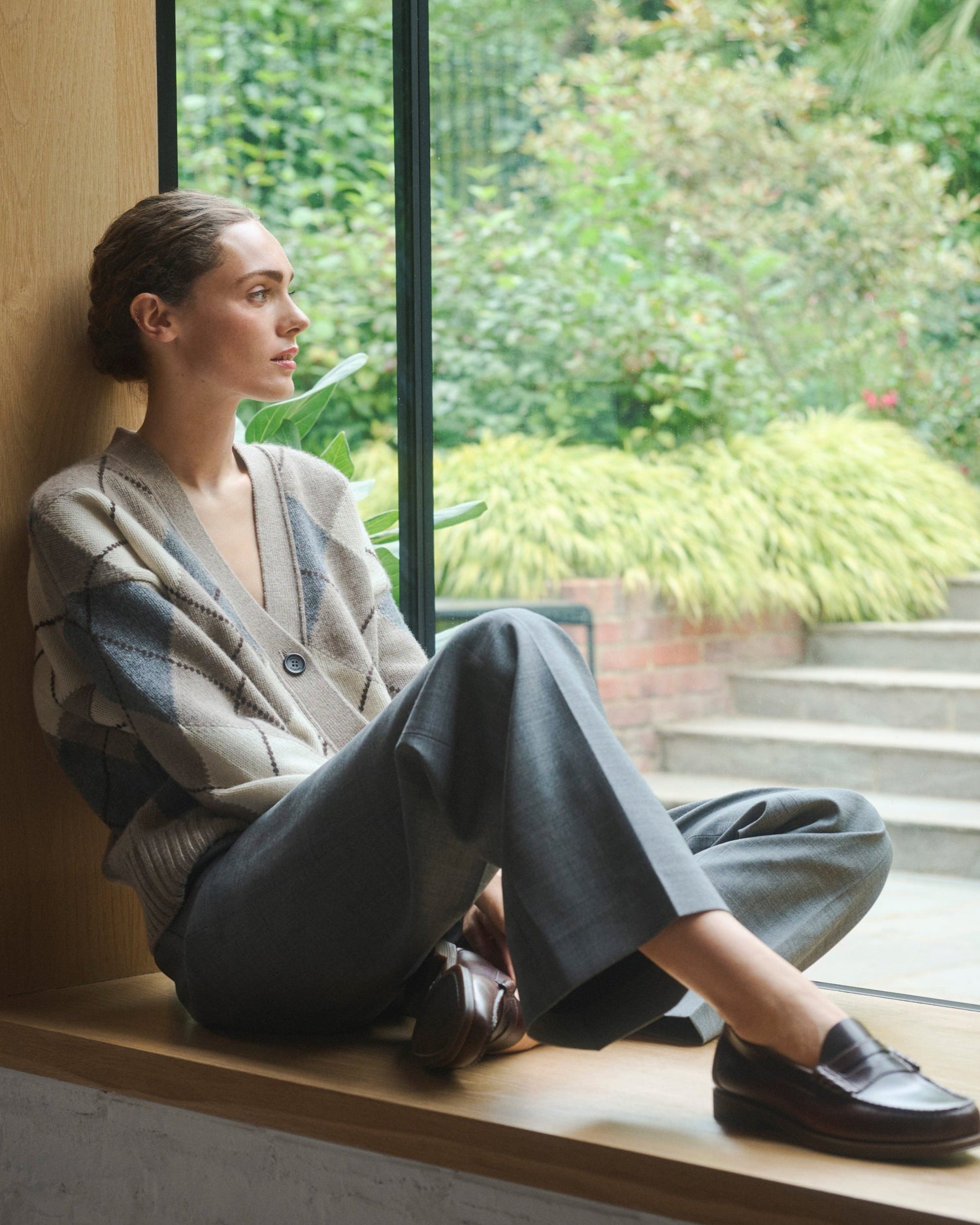 Woman sitting by a window with a view of greenery